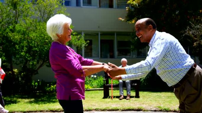 活跃的混血夫妇在养老院4k花园里一起跳舞的侧视图