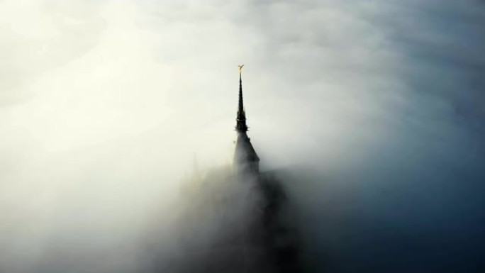 法国诺曼底日出时覆盖雄伟的圣米歇尔山要塞城堡尖顶的浓雾的惊人航拍