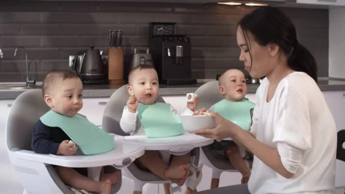 耐心的亚洲妈妈喂养顽固的三胞胎婴儿