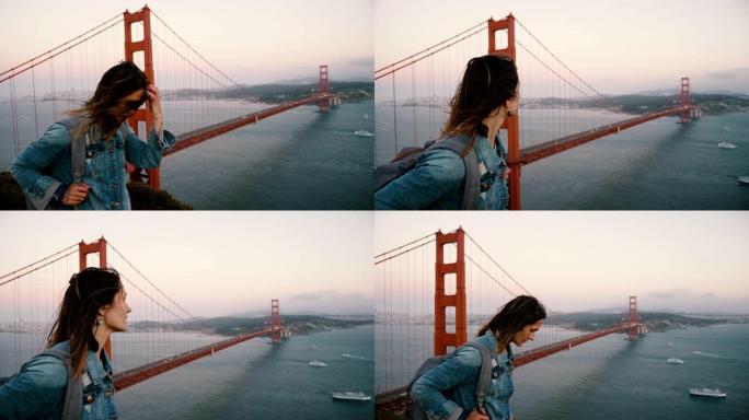 侧景年轻漂亮的旅游女人背包散步看日落风金门大桥的壮丽风景