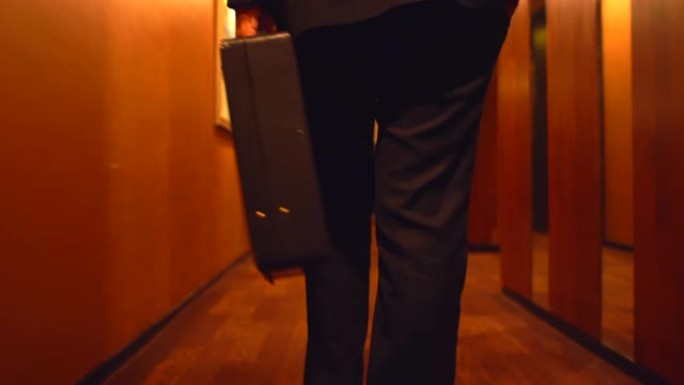 高级商人在办公室里散步的背景图。带着公文包的商人在办公室里散步。用公文包跟进商人的腿。
