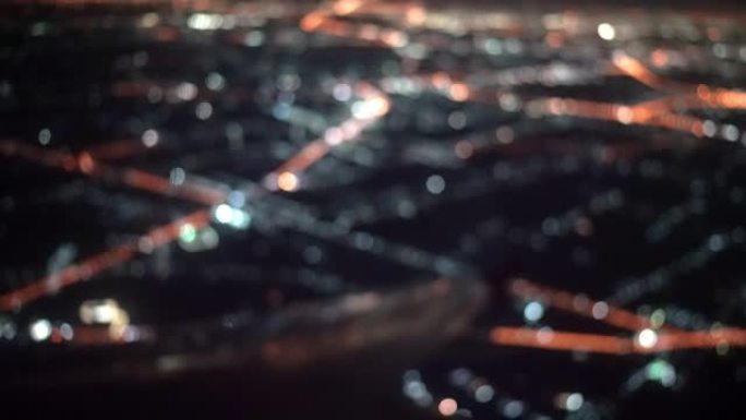 飞机窗景的散焦和夜间飞行的灯光城市照明