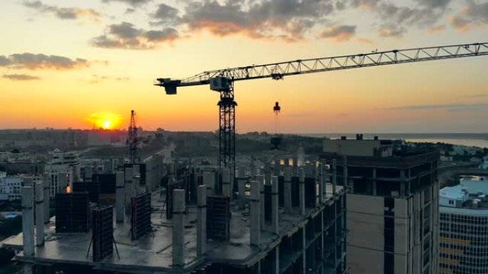 一台起重机在日落背景下的建筑工地上工作。