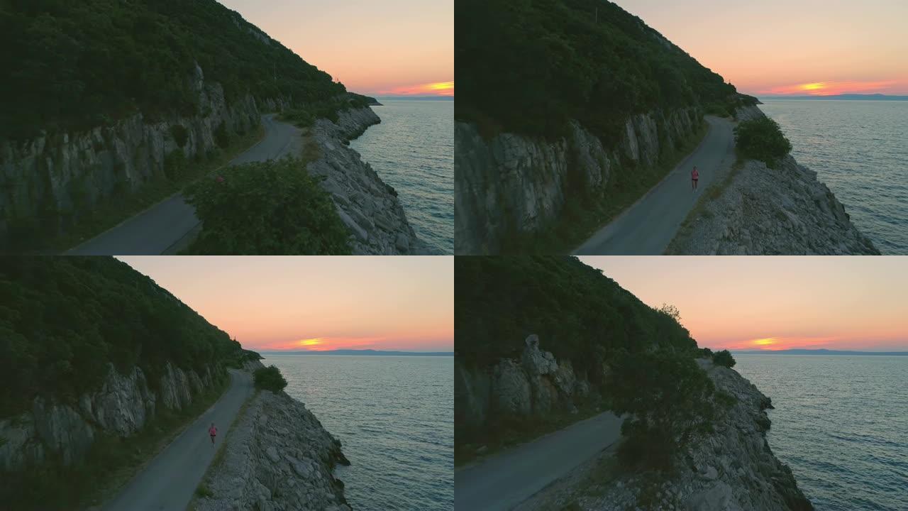 日落时分，空中女子在海边的道路上慢跑