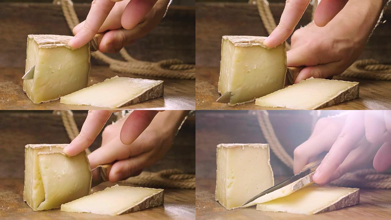 帕尔马干酪组合物，放在木制砧板上。一只手拿着刀，折断几块来品尝质量。