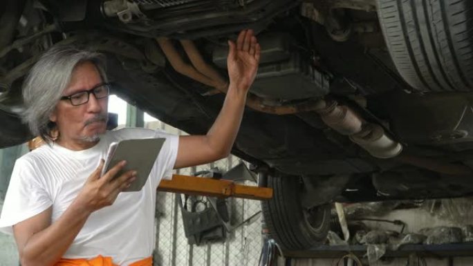 4k: 男性机械师在汽车维修店用平板电脑检查汽车。