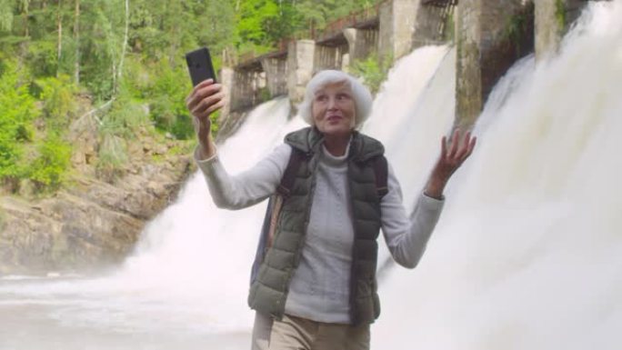 快乐的老年妇女在溢洪道前通过视频通话