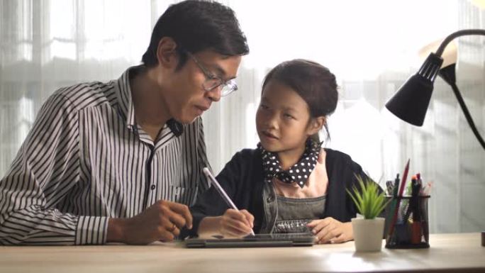 亚洲父亲在家用数字平板电脑教女儿做作业