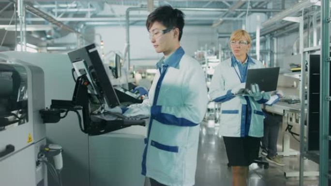 在高科技工厂，亚洲工程师使用计算机编程为印刷电路板表面安装装配线拾取和放置电子机械。用SMT机械生产