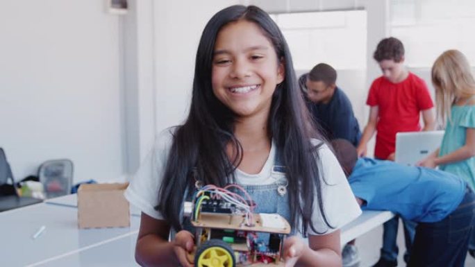 放学后计算机编码班女学生手持机器人车辆的肖像