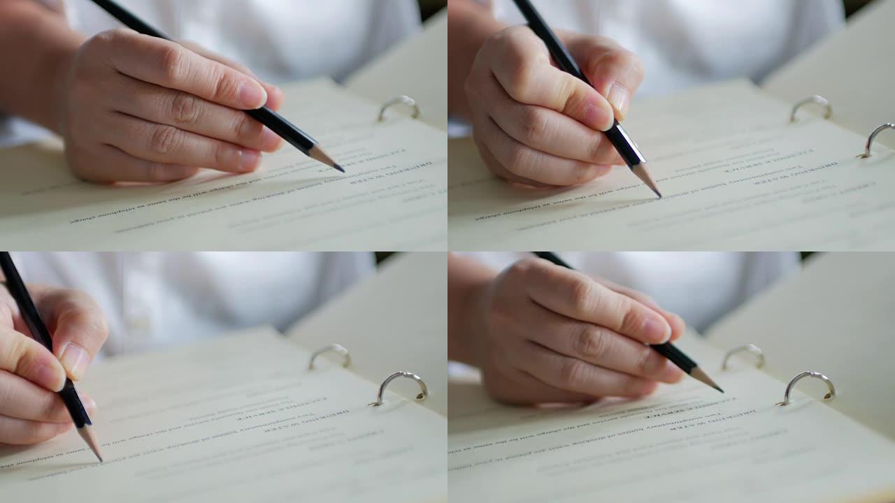女人用笔在记事本上写字，在家工作的特写镜头