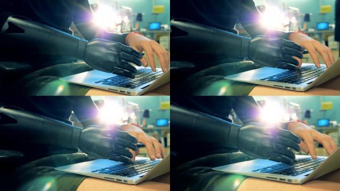 人的人工手在笔记本电脑键盘上打字的特写。半机械人概念。