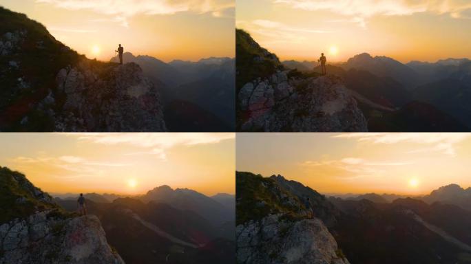 镜头耀斑: 令人惊叹的日落照亮了站在悬崖上的阿尔卑斯山和徒步旅行者。