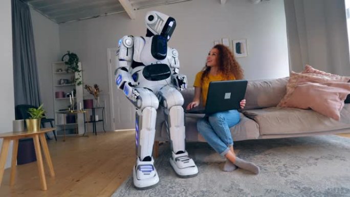 年轻女子正在操作笔记本电脑并与机器人交谈。机器人，类人机器人概念。