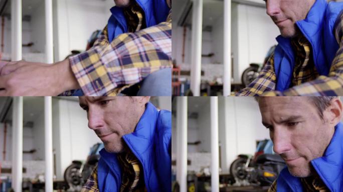 在摩托车维修车库4k中使用手机的男性机械师