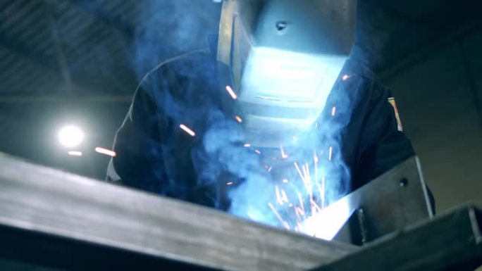 在工作期间，将焊工关闭在防护头盔中。专业重工业焊工在焊接厂工作。
