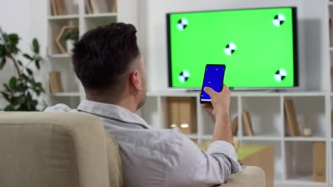 男人使用智能手机和绿屏看电视