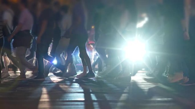 行人在人行横道上行走。晚上在城市斑马线街上面目全非的人。慢动作镜头，4K