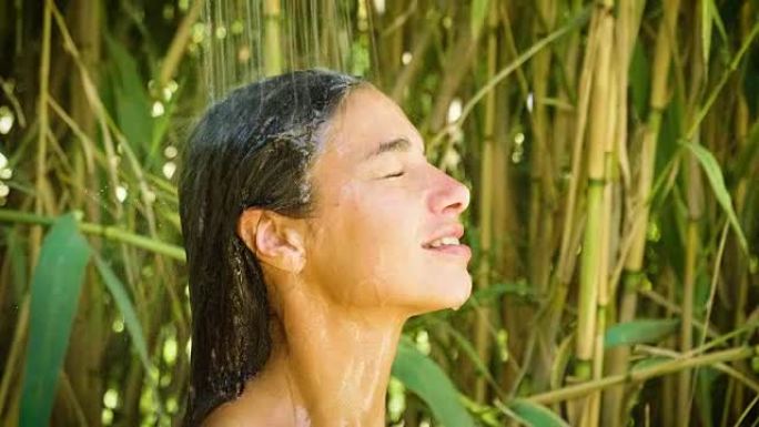 大自然中年轻美丽的女孩在温暖透明的热带瀑布中自然淋浴下洗涤。