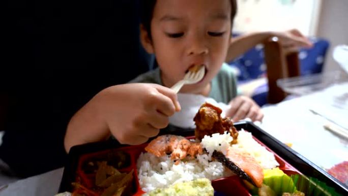 亚洲孩子在当地的房子里吃日本食物。