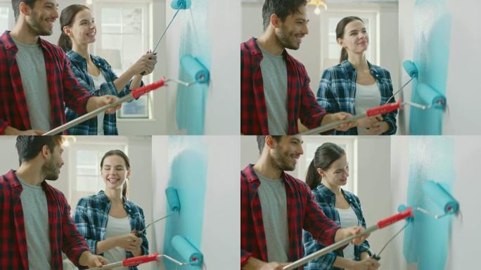 年轻漂亮的夫妇装饰他们的新公寓。丈夫和妻子正在用蘸有浅蓝色油漆的滚筒粉刷墙壁。家里的装修。