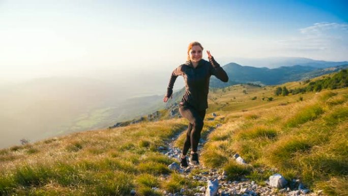 身体意识强的女运动员在岩石小径和草坡上奔跑，背景为绿色草地