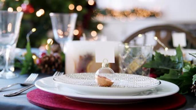 特写镜头，摆设在圣诞餐桌上的盘子上的摆设名片夹，背景为bokeh圣诞灯