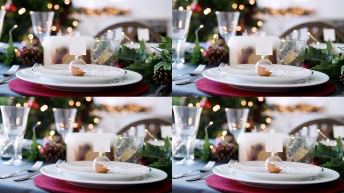 特写镜头，摆设在圣诞餐桌上的盘子上的摆设名片夹，背景为bokeh圣诞灯