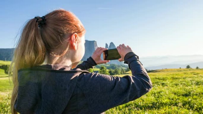 度假的女游客用智能手机拍摄分层山脉的照片