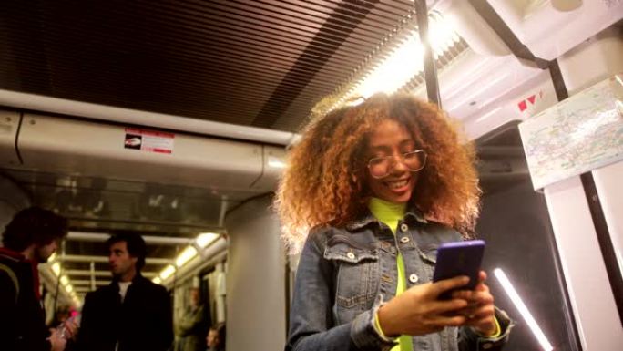年轻的黑人妇女在火车上旅行时使用智能手机