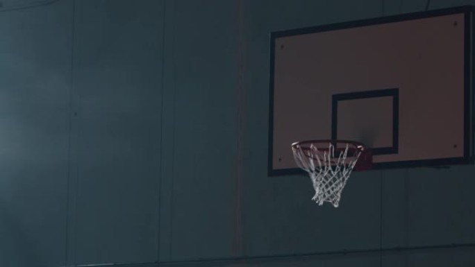一名年轻职业男球员的电影慢动作镜头正在健身房进行篮球锻炼时扣篮