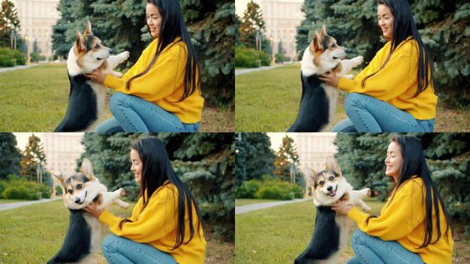 年轻的亚洲女士在公园里和美丽的柯基犬玩耍，拥抱动物