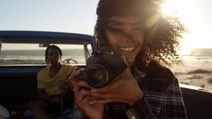 女人在4k海滩的皮卡车上用数码相机拍照