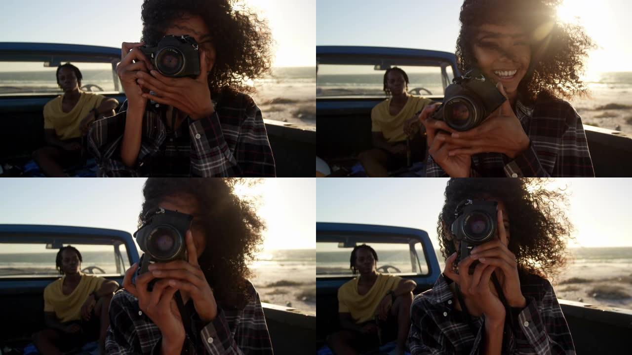 女人在4k海滩的皮卡车上用数码相机拍照