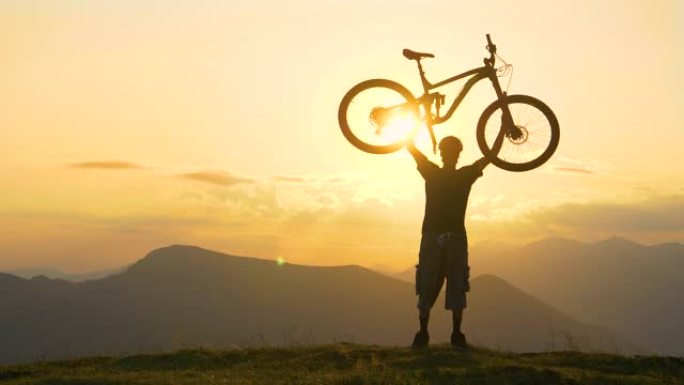 慢动作: 年轻的男性自行车手在金色日落时将自行车放在头顶。