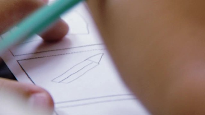 一个小学生用铅笔画纸的手。