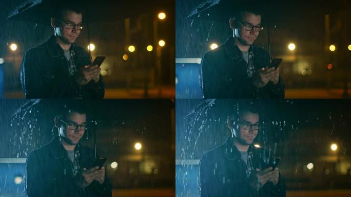 戴着眼镜的白人年轻人，穿着牛仔裤外套和方形衬衫，正在雨伞下使用智能手机。外面很黑，正在下雨。