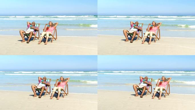 活跃的老年非洲裔美国夫妇在4k海滩躺椅上喝酒的前视图