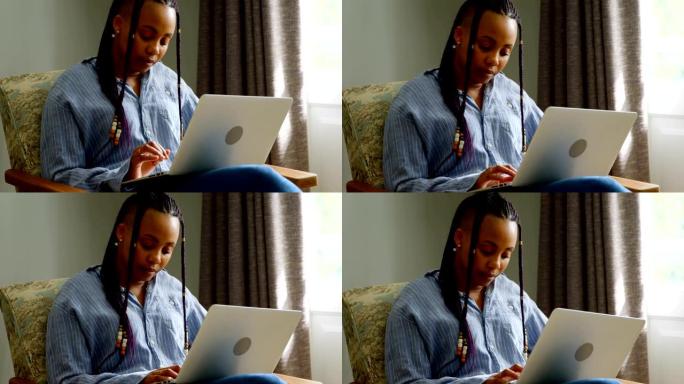 在舒适的家庭4k中工作的年轻黑人妇女在笔记本电脑上的前视图
