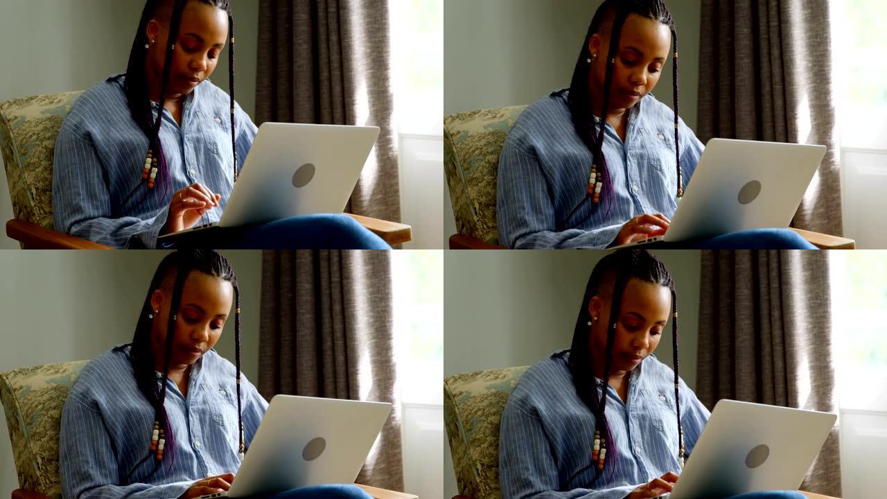 在舒适的家庭4k中工作的年轻黑人妇女在笔记本电脑上的前视图