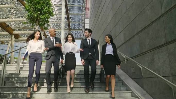 一群穿着西装和领带的不同种族的商人离开办公室后自豪地走着。