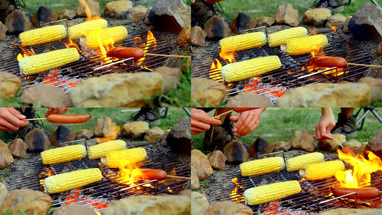 朋友在篝火上烤热狗和玉米的特写4k