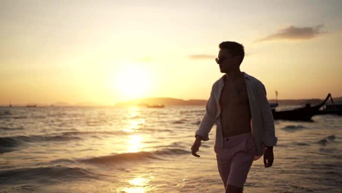 男人在沙滩上散步夕阳西下落日余晖肌肉男
