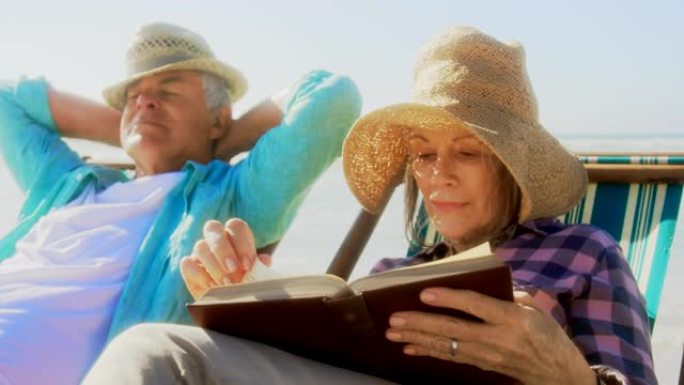 活跃的白人女性在海滩上看书的前视图4k