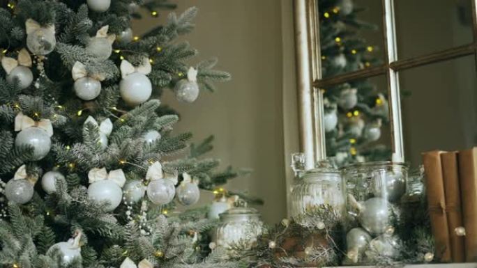 完美圣诞装饰壁炉架的特写镜头，配有配件和绿色新年树，树枝上有银球和灯。节日快乐概念。