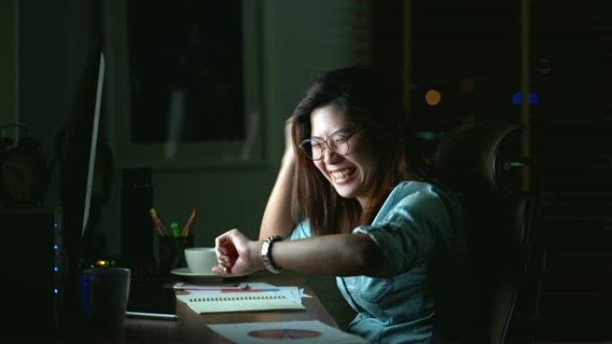 4k镜头迷人的亚洲女人的场景工作到很晚才能在桌子前完成工作在黑暗中的工作场所的电脑显示器桌面上的快乐