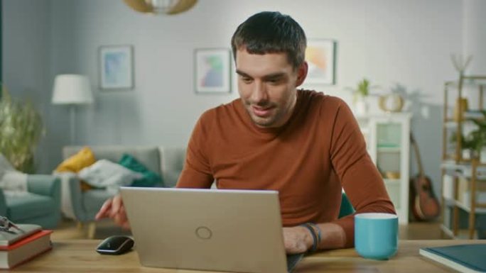自信的年轻人坐在家里的办公桌前，打开并开始使用笔记本电脑。背景客厅设计舒适。