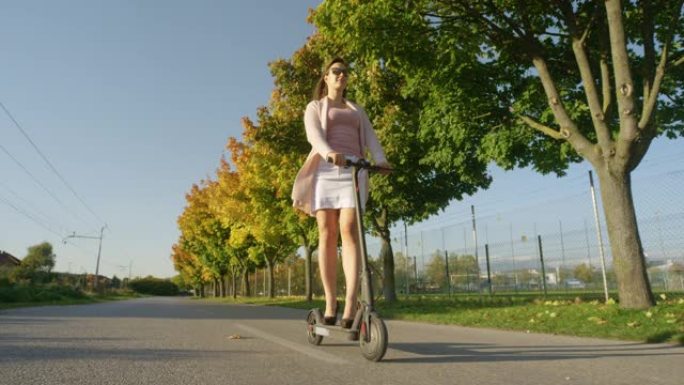 低角度: 穿着黑色高跟鞋的快乐白人妇女骑着电动踏板车。