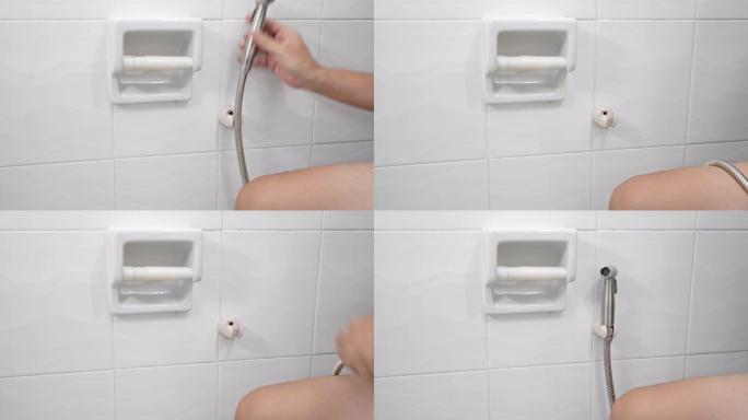 一个在厕所里使用坐浴盆淋浴的人。坐浴盆喷雾清洁浴室抽水马桶。