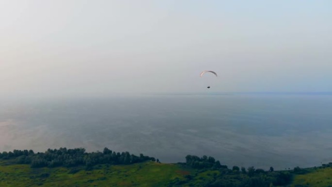 一名运动员带着滑翔伞在田野上空飞行。空中滑翔伞。